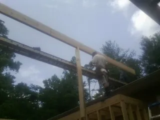 Carpenter setting a ridge beam over a new addition frame — Ice Dam Removal by Roofing Brothers in Forestville