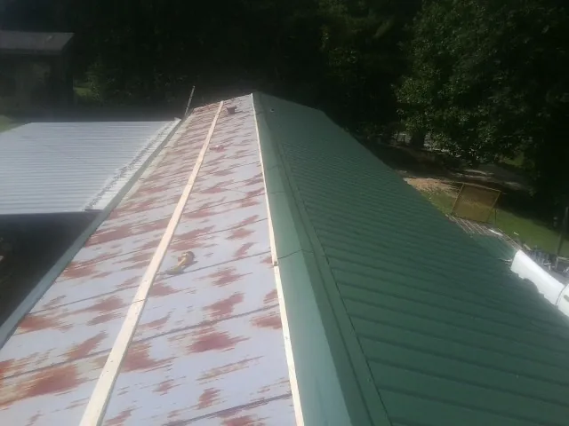 Old rusted panels beside newly installed green metal roofing — Wind Damage Roof Repair by Roofing Brothers in Forestville
