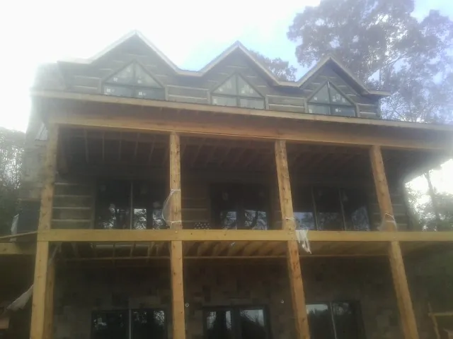 Dormers and porch framing on a large log home under construction — Roof Coating work by our crew in Forestville