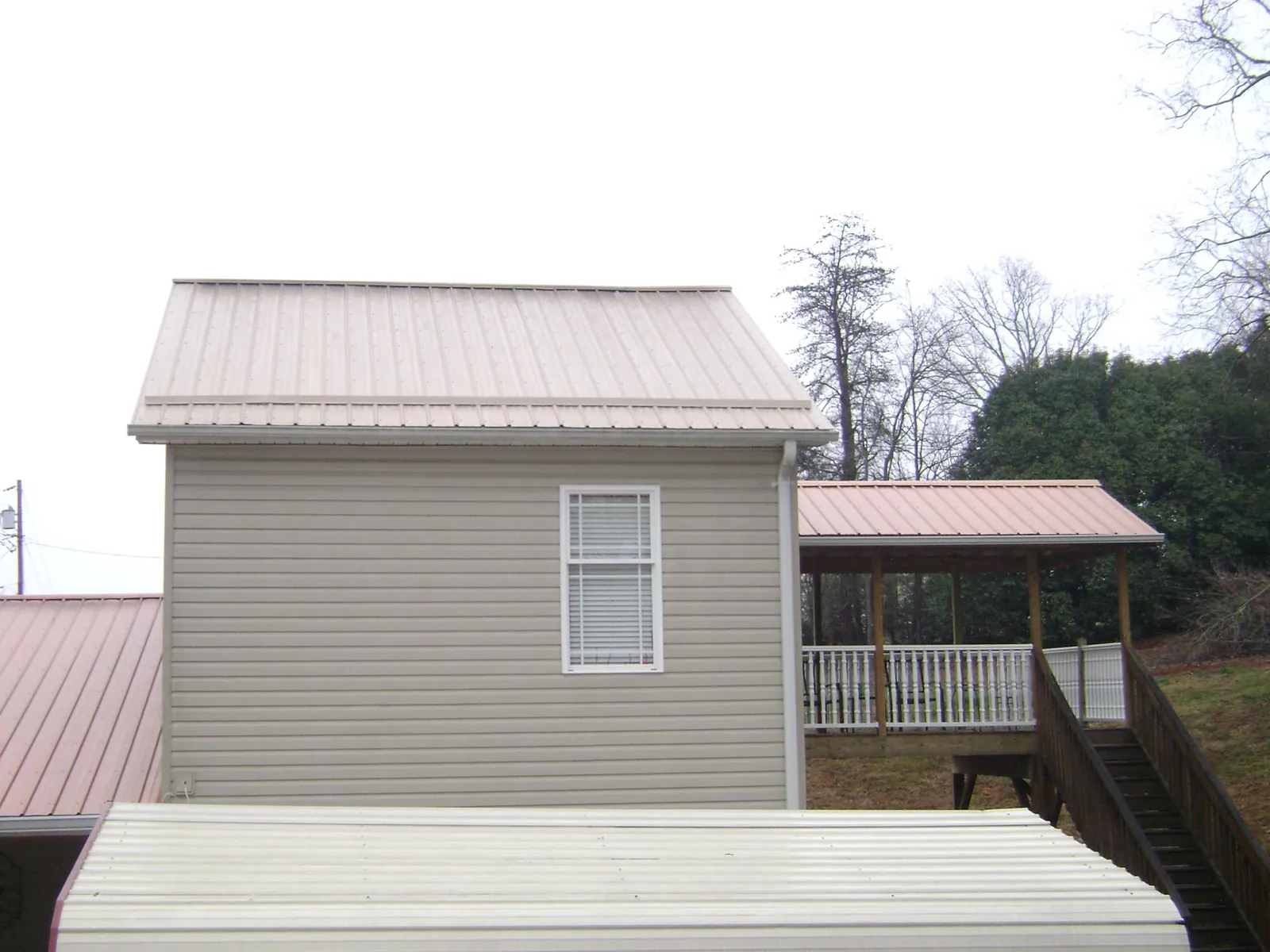 Tan metal roofs on a two story addition and attached porch, from a Roof Replacement job in Forestville