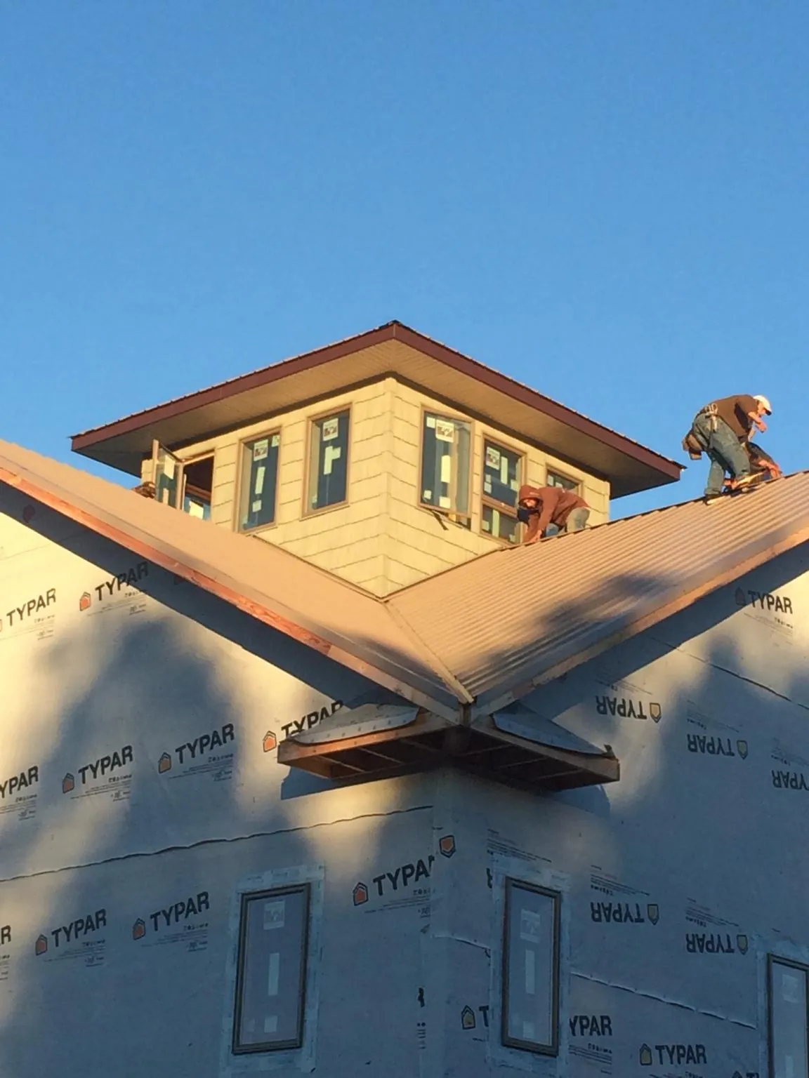Roofers working around a rooftop cupola on a new metal roof at sunset — Roof Waterproofing in Forestville by Roofing Brothers